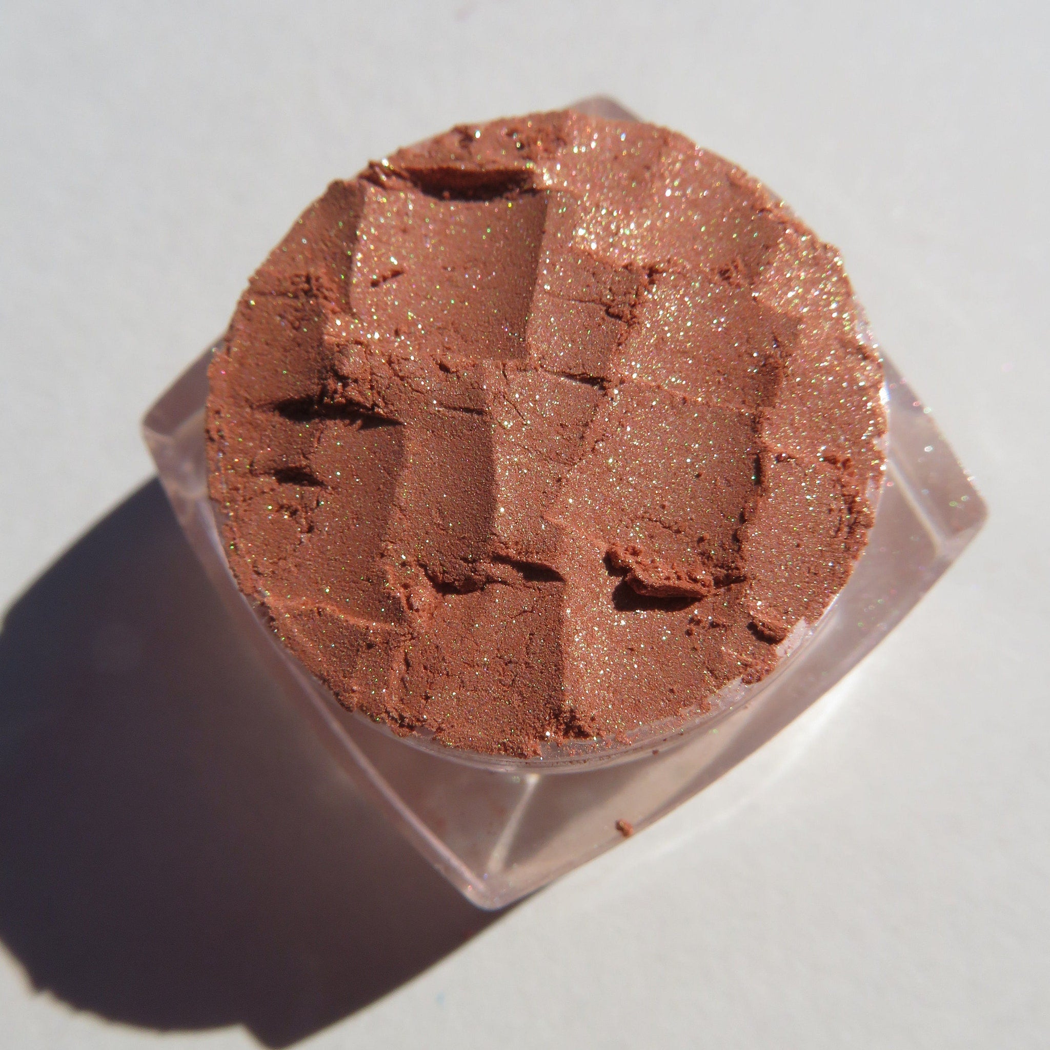 Open jar of brown gold loose mineral eyeshadow with golden shimmer, vegan label visible