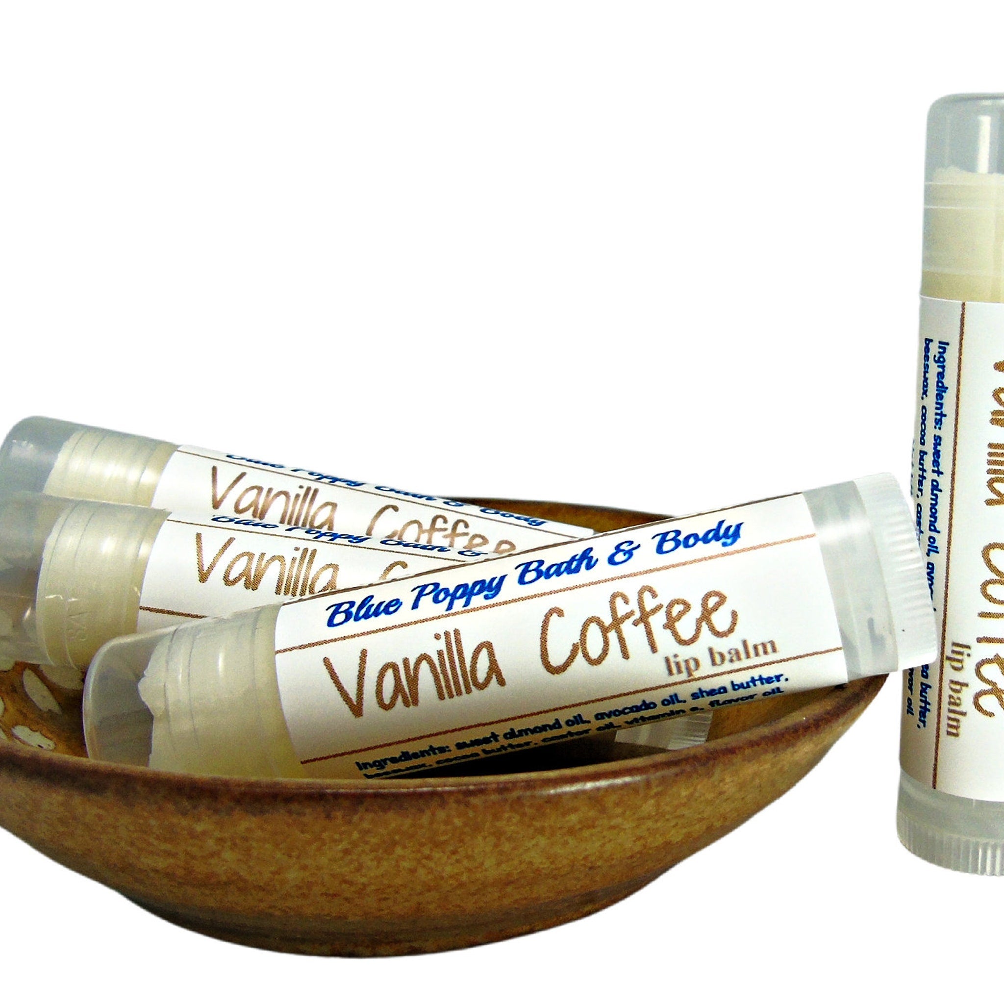 Lip balm tubes with white labels, brown text, and clear plastic packaging, in a brown bowl.