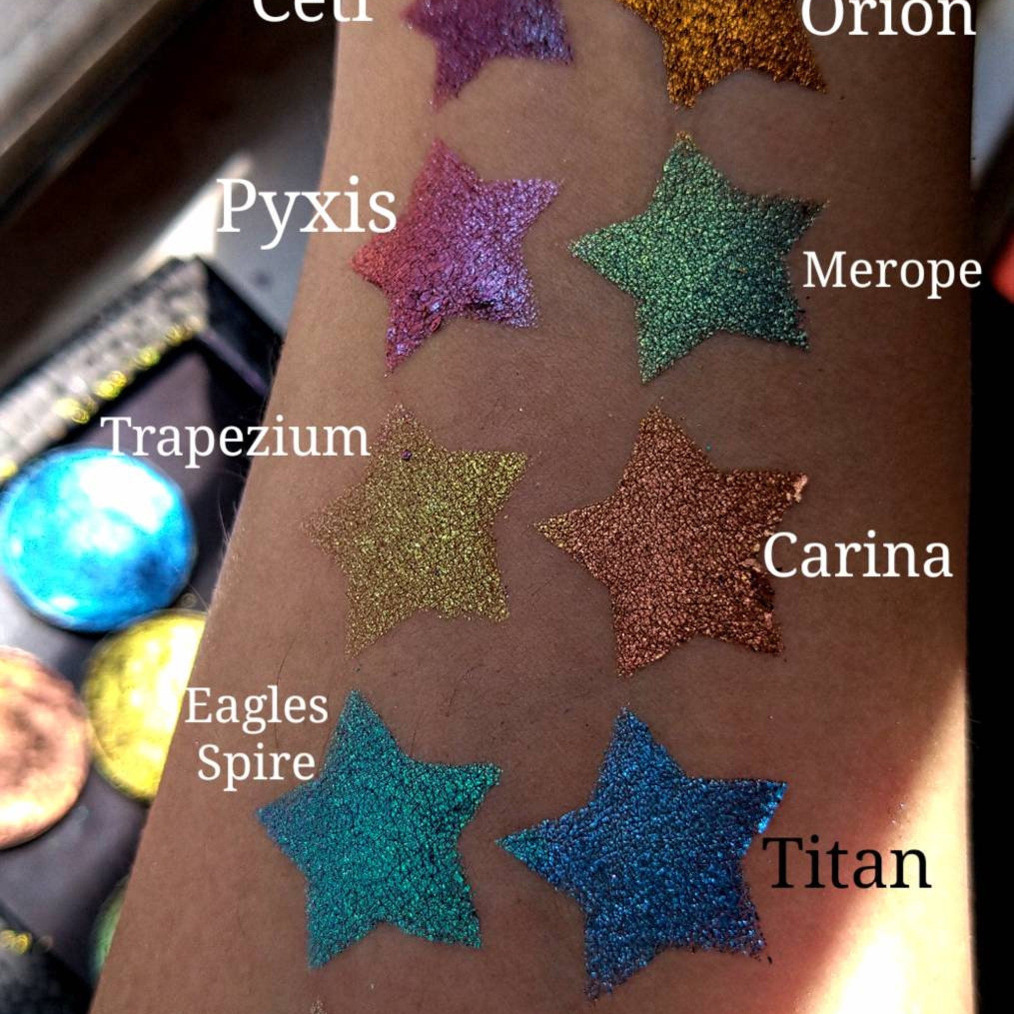 Open cardboard palette displaying six multichrome pressed eye shadows with color-shifting shimmer