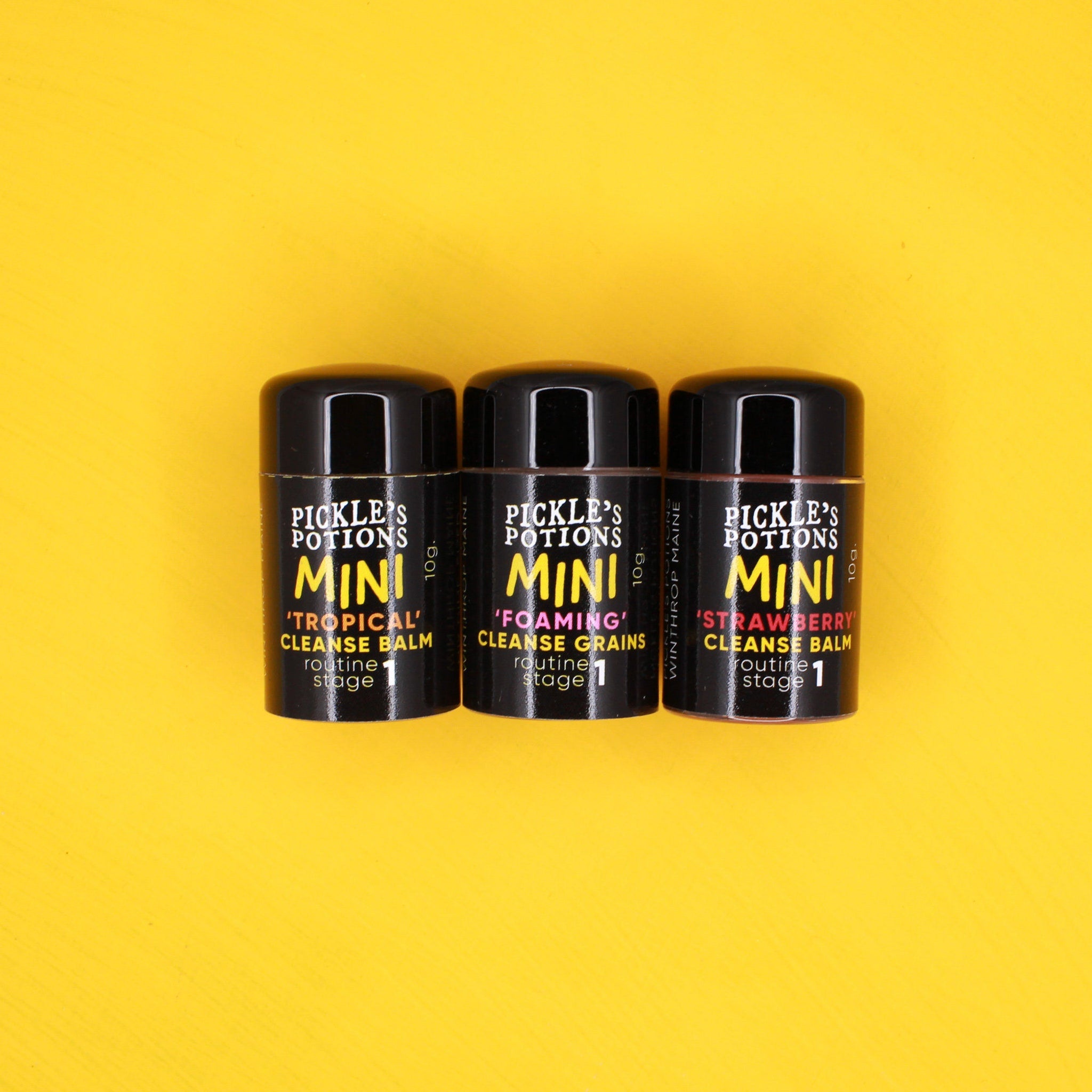 Mini cleanse balm bottles, black cylindrical containers, Pickle's Potions brand, yellow and white text labels