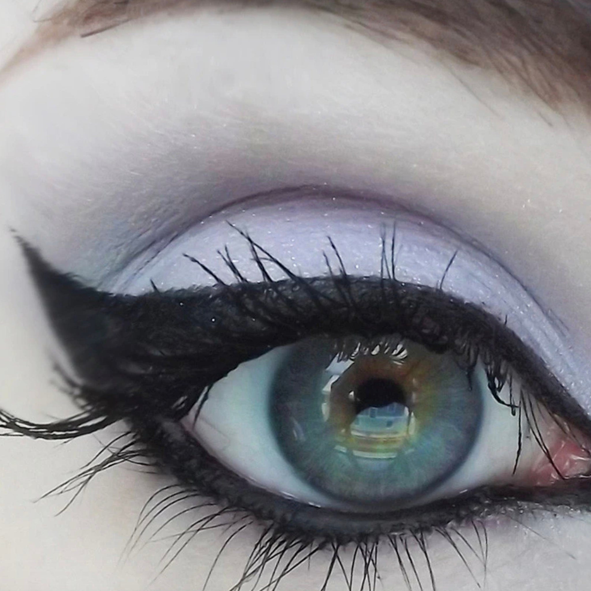 Eye makeup close-up with black eyeliner and mascara, blue and purple eyeshadow, and green eye color