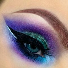 Eye makeup with purple, teal, and black eyeshadow, white eyeliner, and long black lashes