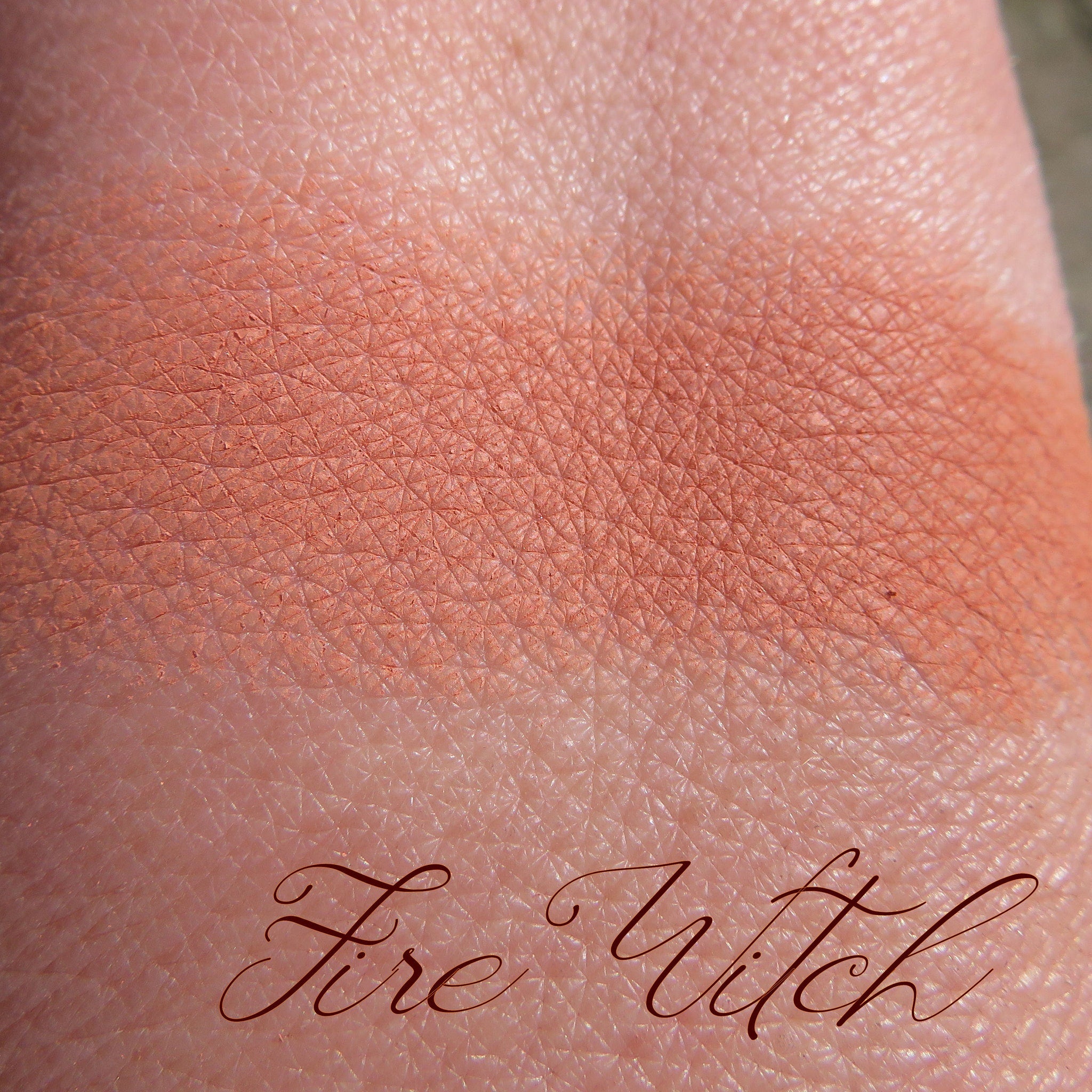 Close-up of loose burnt orange mineral eyeshadow powder spilling from eco-friendly jar