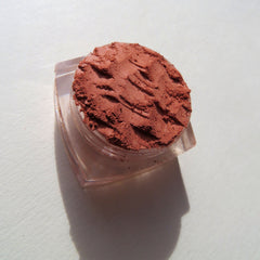 Side view of burnt orange mineral eyeshadow in matte finish, showcasing loose pigment texture in eco-friendly packaging