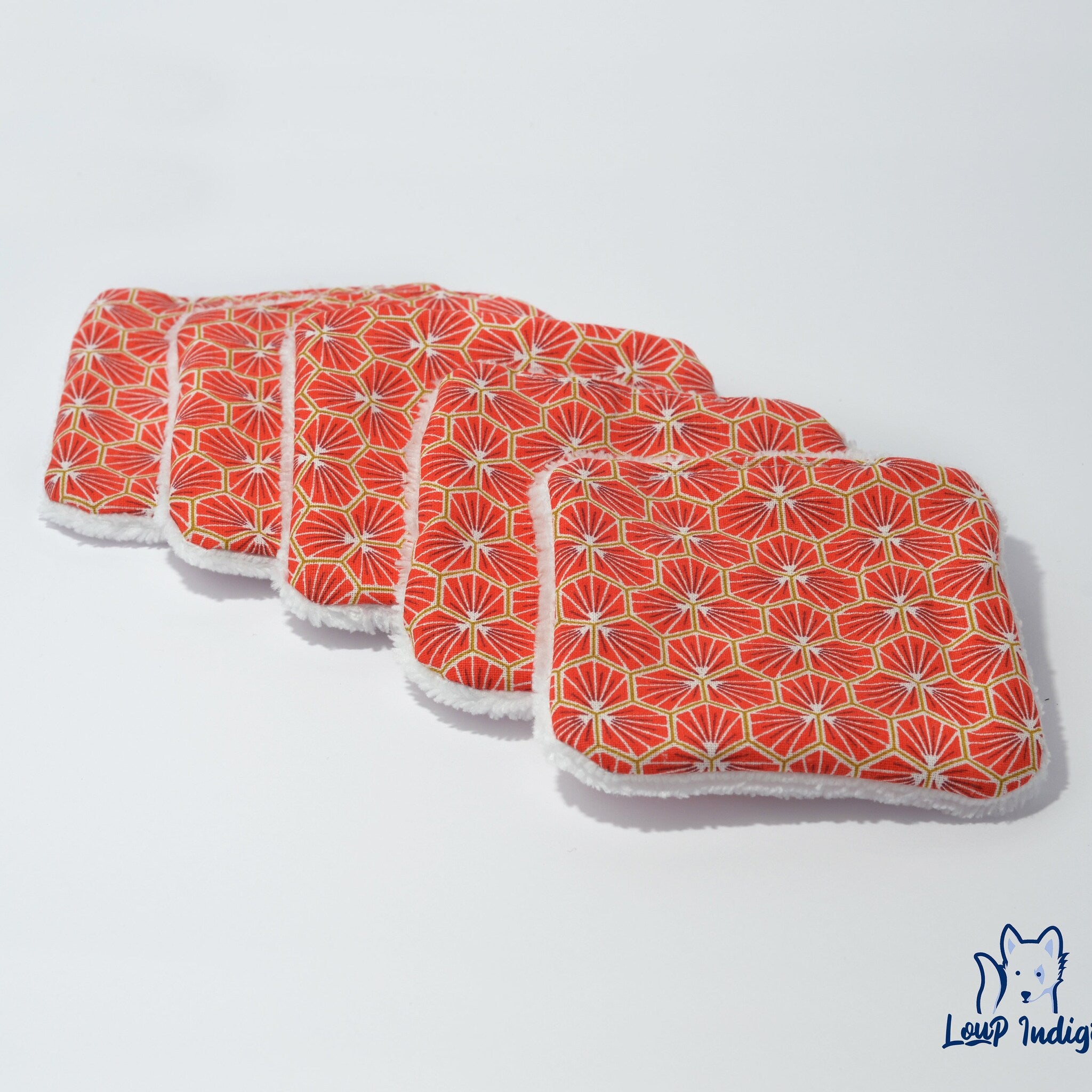Reusable pads with red geometric pattern and white fluffy trim, Loup Indigo logo visible