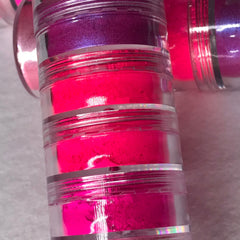 Close-up of six neon pink eyeshadows with matte and shimmer finishes in a sleek black palette