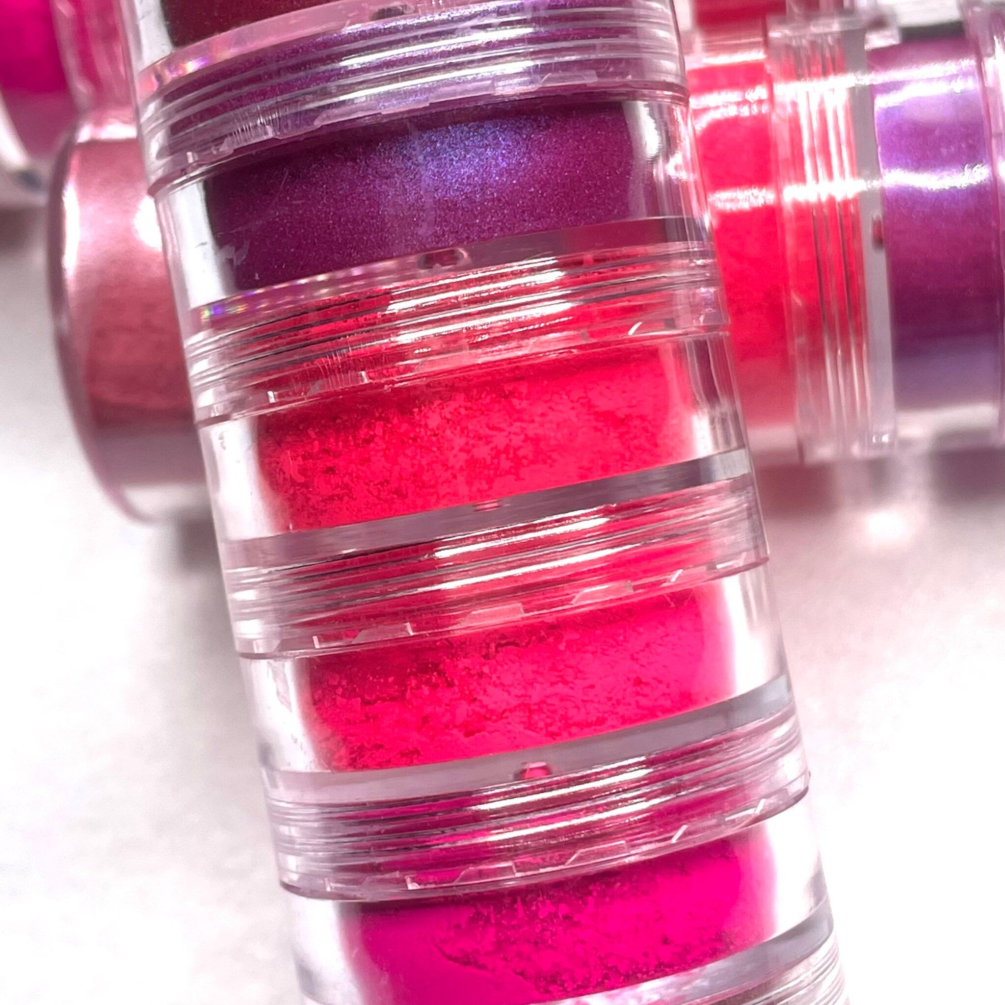 Hand applying shimmering neon pink eyeshadow with a blending brush onto eyelid