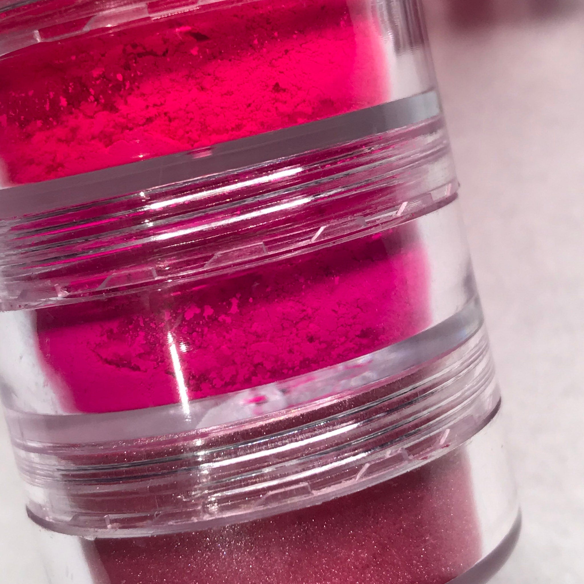 Side view of neon pink eyeshadow stack showing six vibrant matte and shimmer shades in compact palette