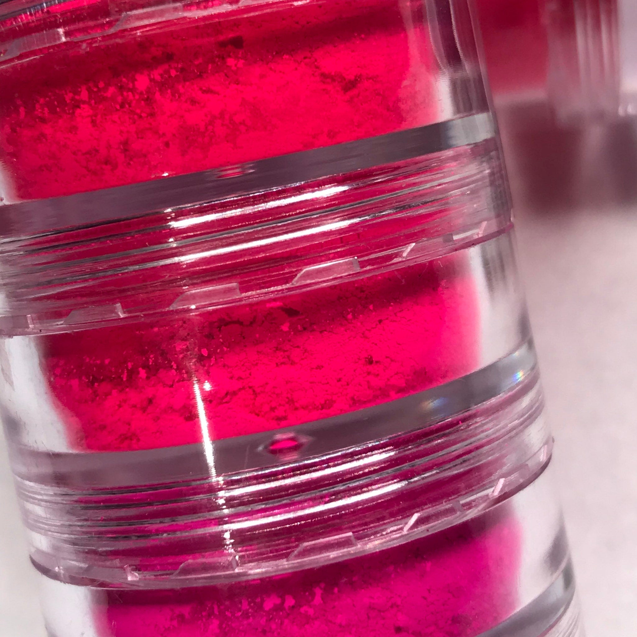 Side view of neon pink eyeshadow stack showing six vibrant matte and shimmer shades in compact palette
