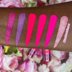 Side view of six neon pink eyeshadow pans in matte and shimmer finishes, arranged in a sleek black compact