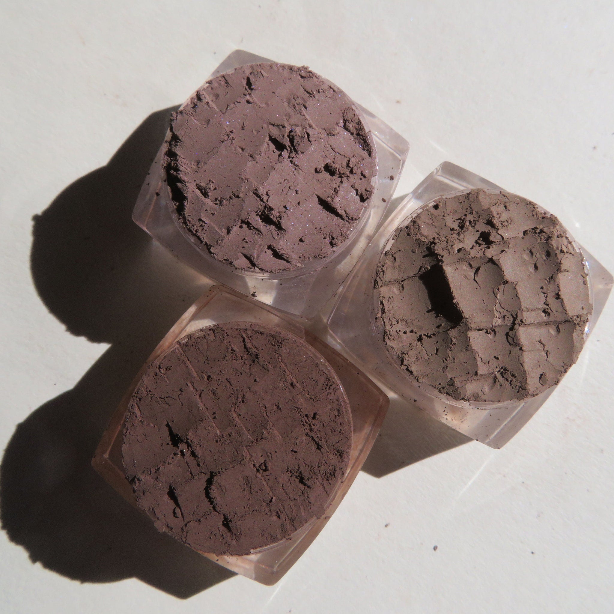 Close-up of matte brown loose mineral eye shadow powder with fine texture in a small open jar