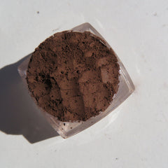 Close-up of matte brown loose mineral eyeshadow powder with soft texture in a small open jar