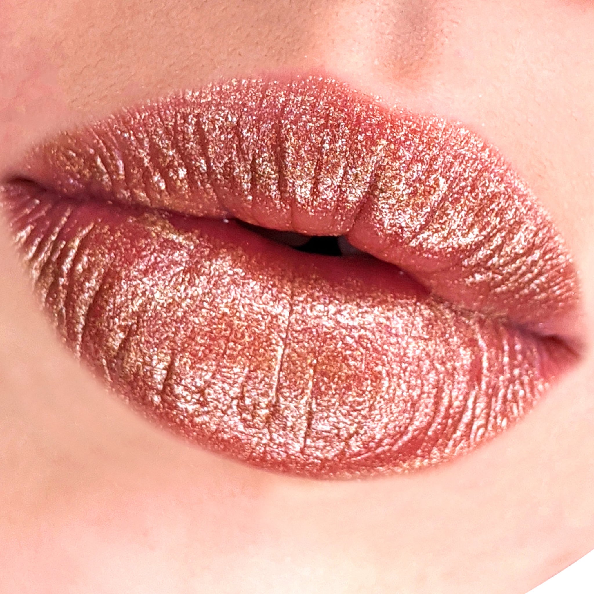 Lip gloss with glitter finish, metallic rose gold color, and textured appearance on lips