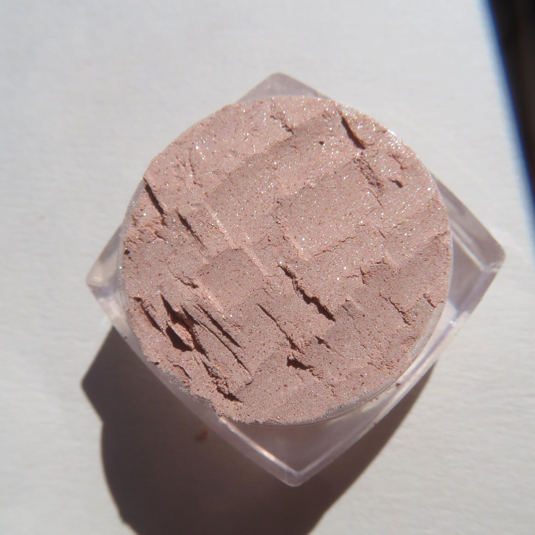 Close-up of loose shimmer eyeshadow in frosty golden champagne beige with reflective mineral particles