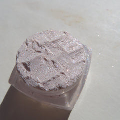 Hand applying sheer pink sparkly glitter eyeshadow to eyelid with fingertip, showcasing shimmer effect
