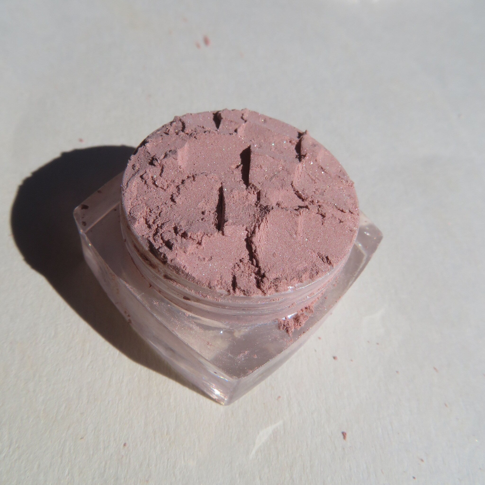 Hand applying sandy brown shimmer mineral eyeshadow with a fluffy brush for a soft, blended look