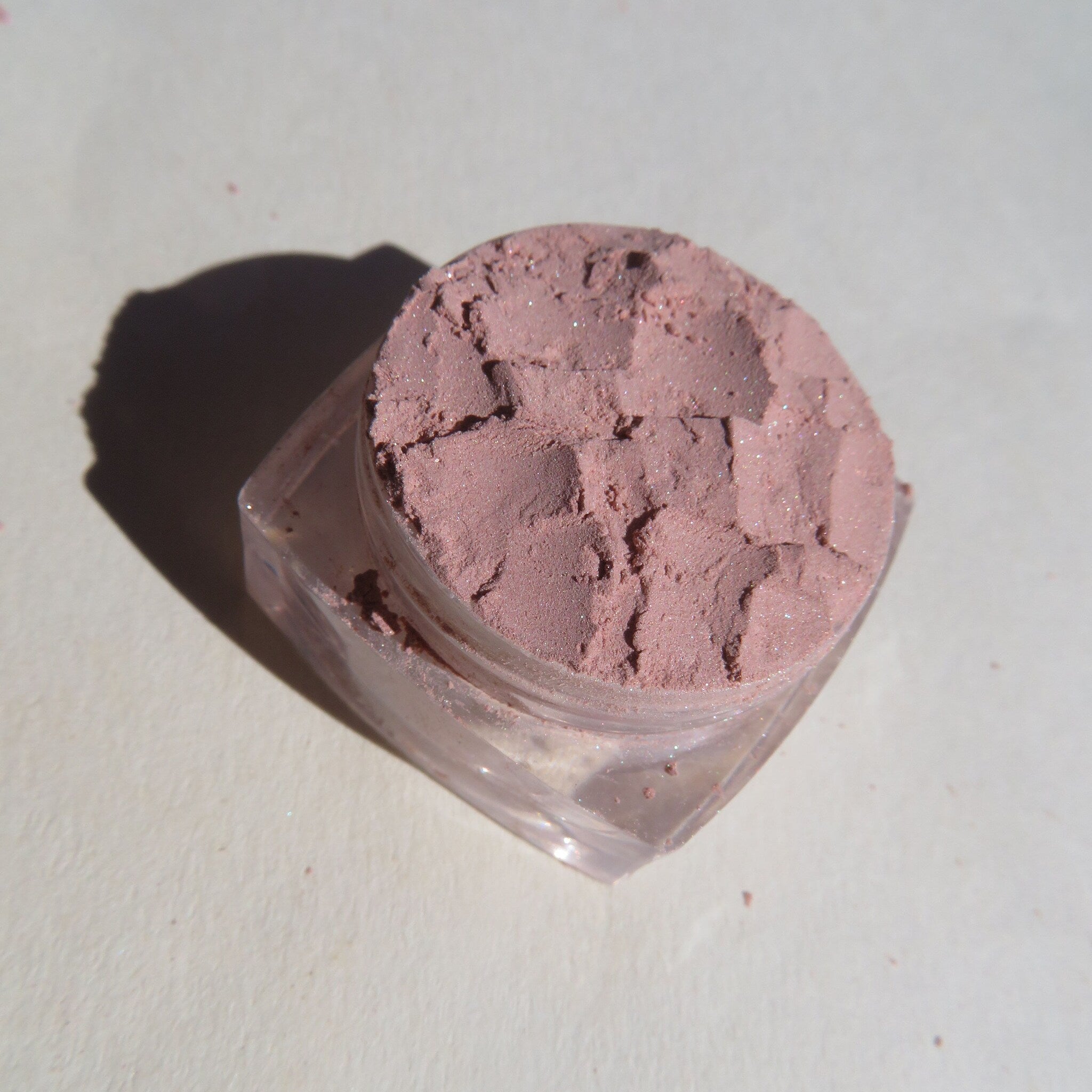 Side angle of sandy brown shimmer mineral eyeshadow in loose pigment form, showcasing its vegan and cruelty-free packaging