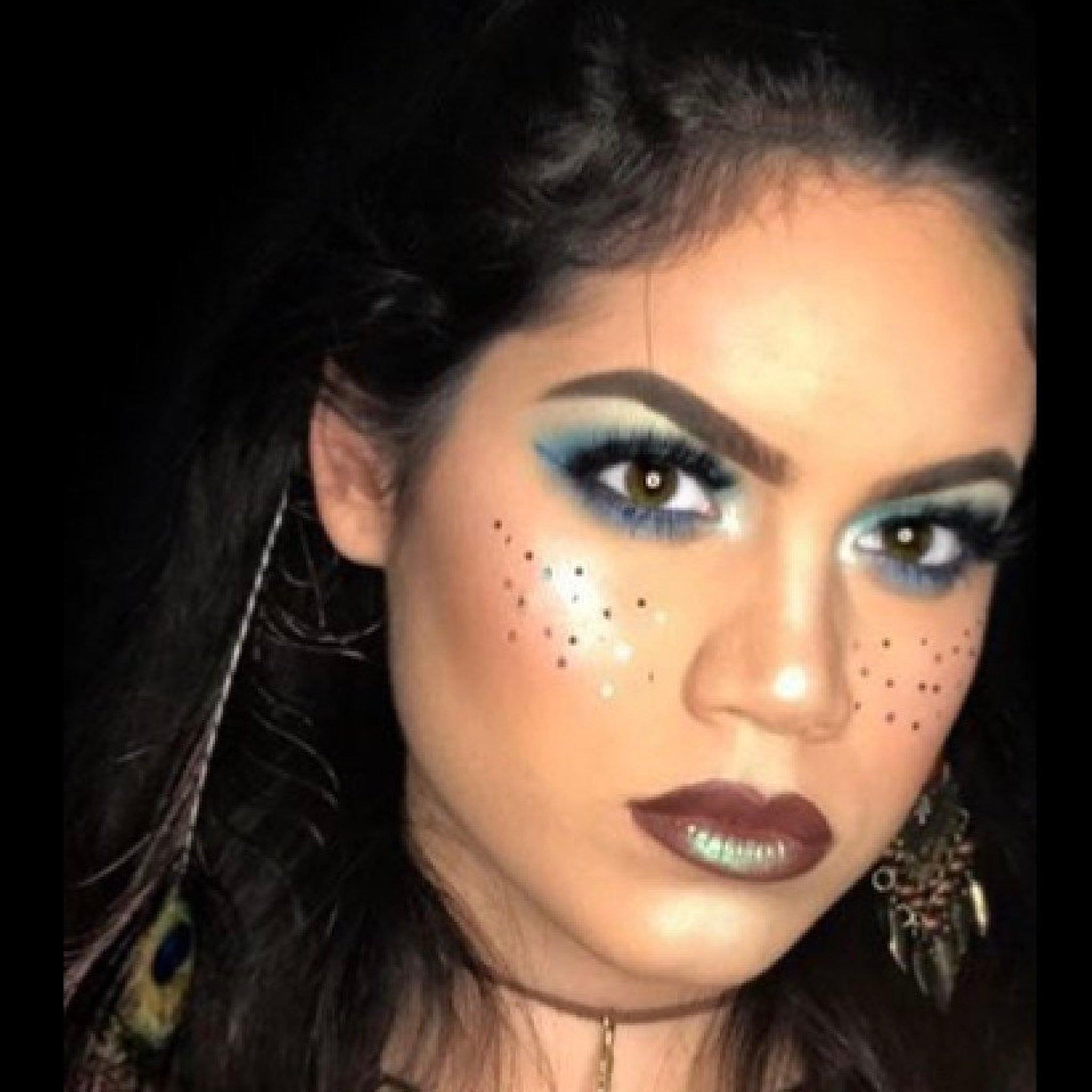 Makeup look with blue eyeshadow, brown lipstick, and freckles on a face
