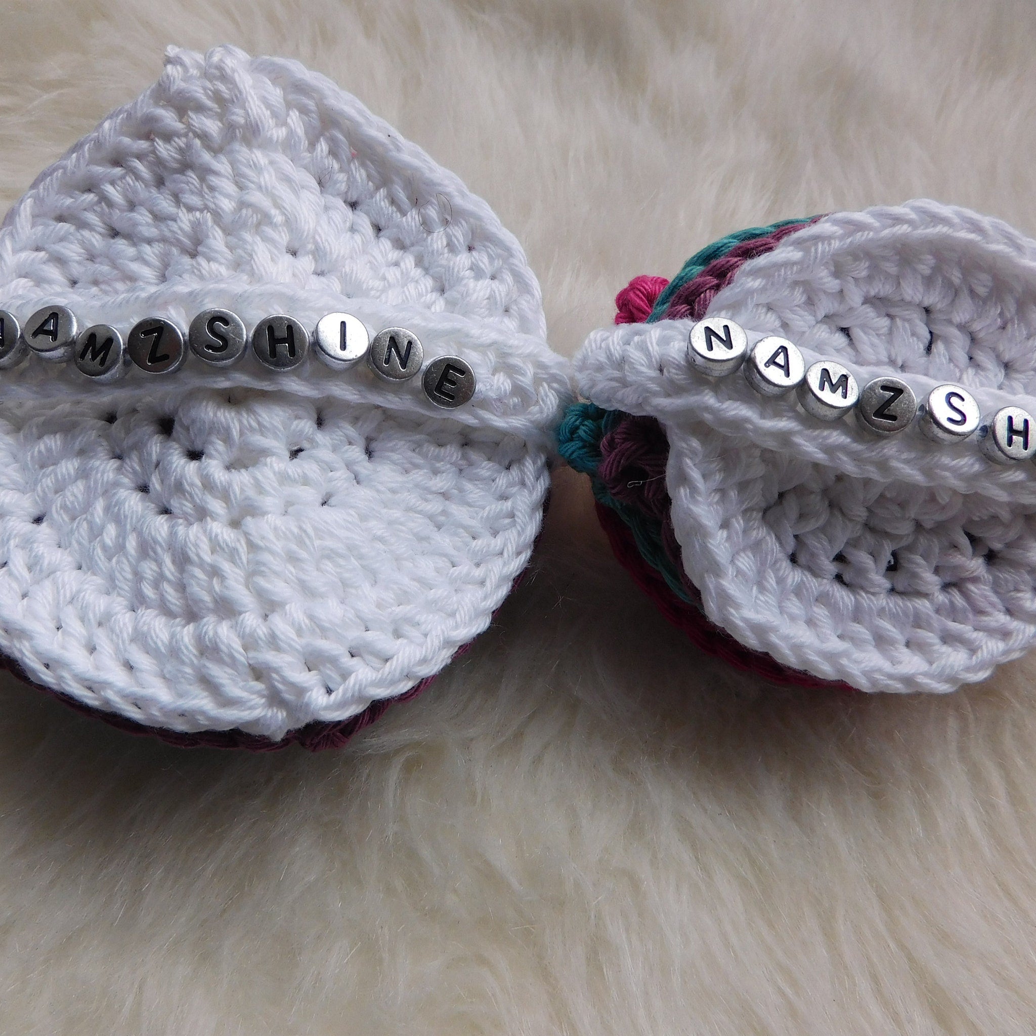 Crochet hats white with beaded lettering, multicolor trim, on a fluffy surface