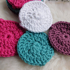 Crochet coasters in white, pink, teal, and purple cotton yarn, handmade style