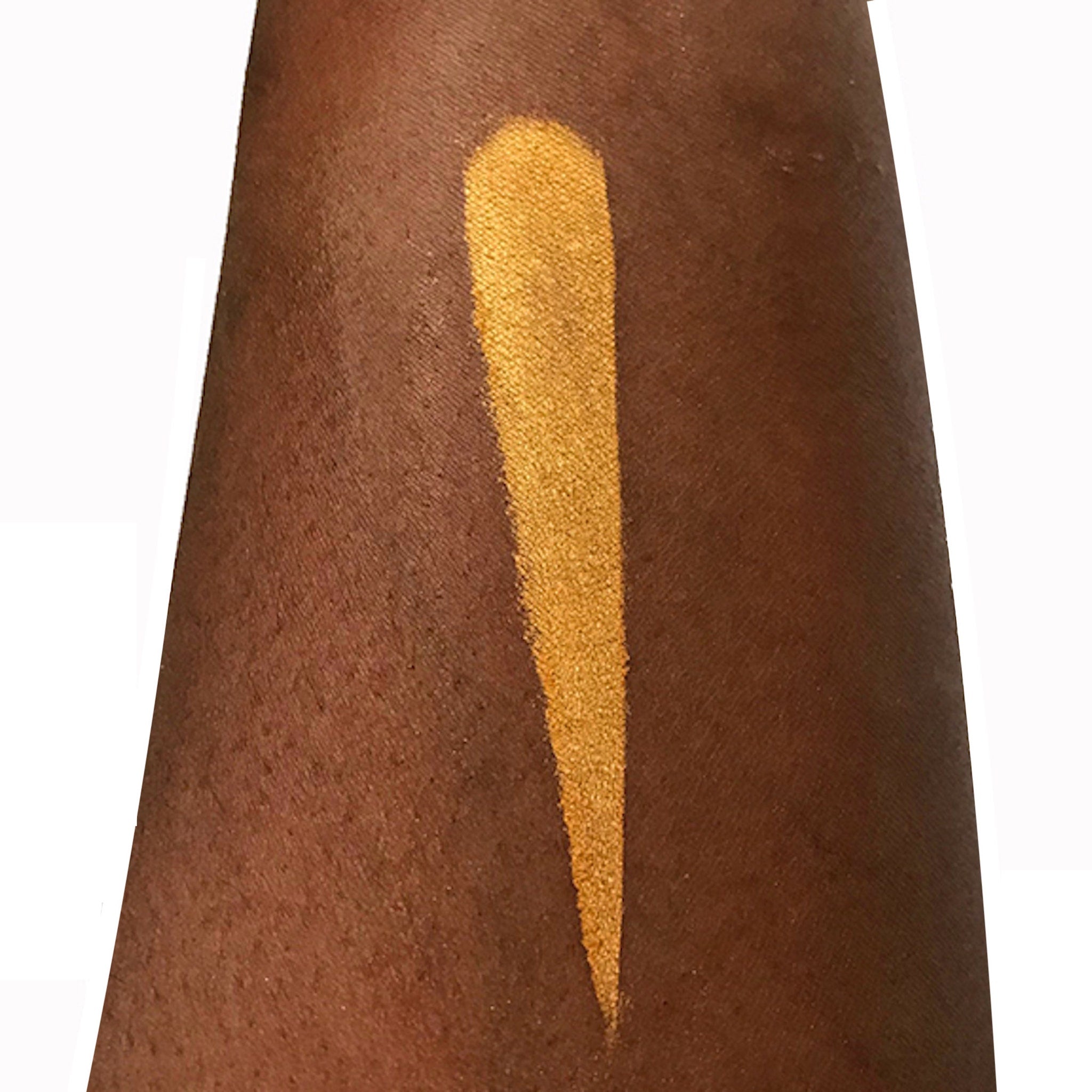 Gold eyeshadow swatch on dark skin, showing color and texture on arm