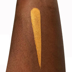 Gold eyeshadow swatch on dark skin, showing color and texture for makeup application