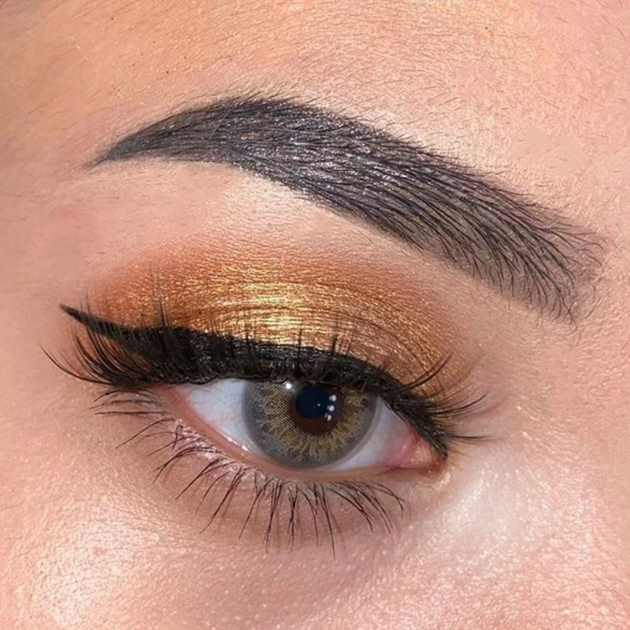 Eye makeup with gold eyeshadow, black eyeliner, and dark eyebrow detail
