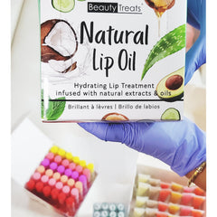 Lip oil box with white background, Beauty Treats branding, and natural ingredient illustrations being held by a gloved hand