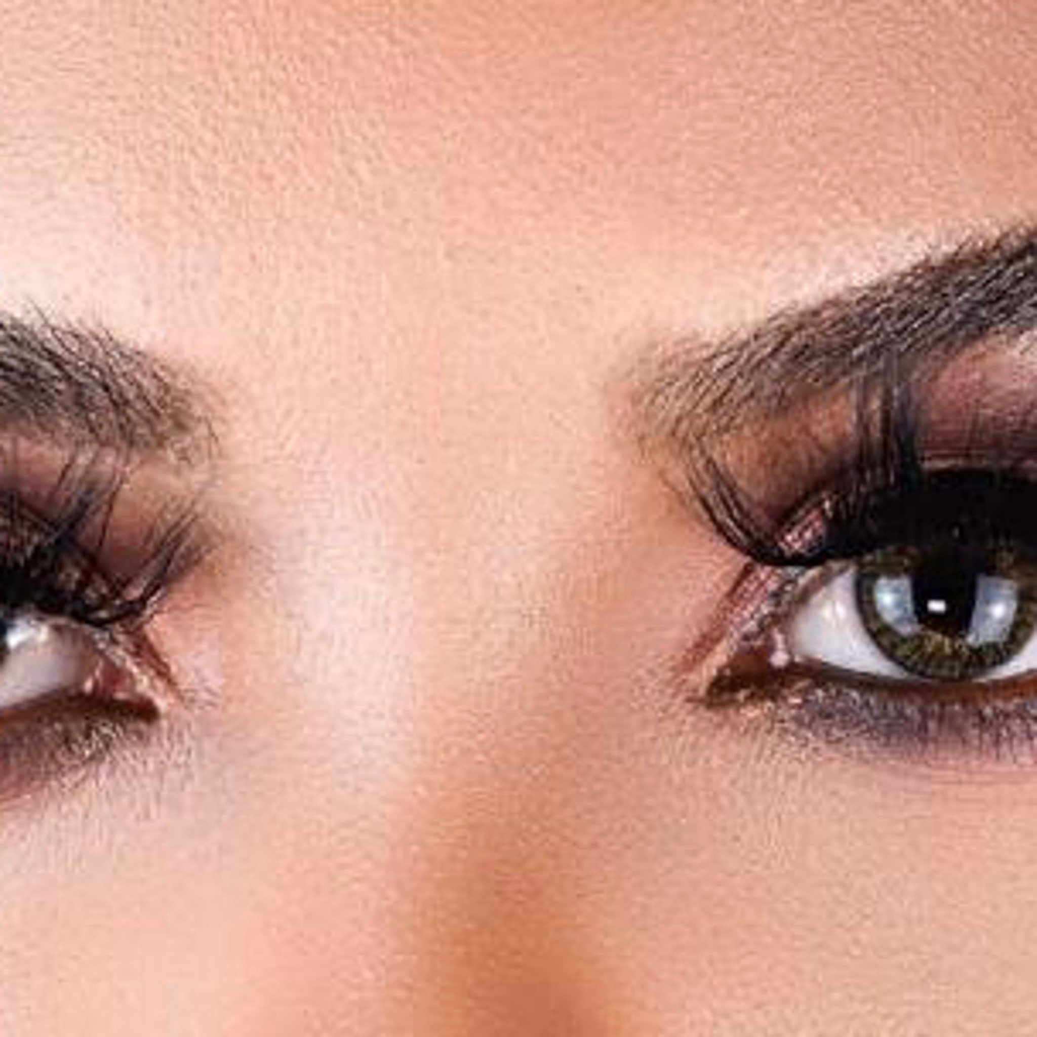 Eye makeup with dark eyeshadow, long false eyelashes, and brown eyes close-up view