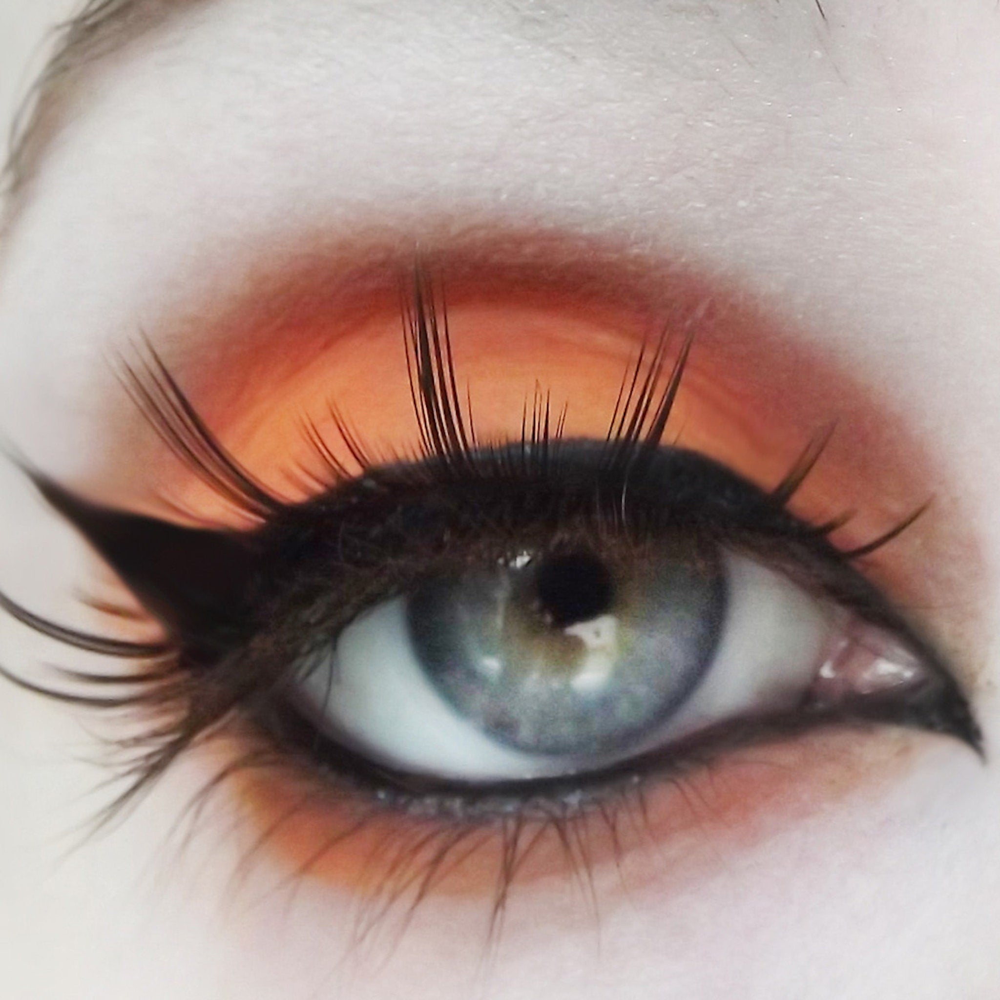 Eye makeup with orange shadow, black eyeliner, and long black eyelashes
