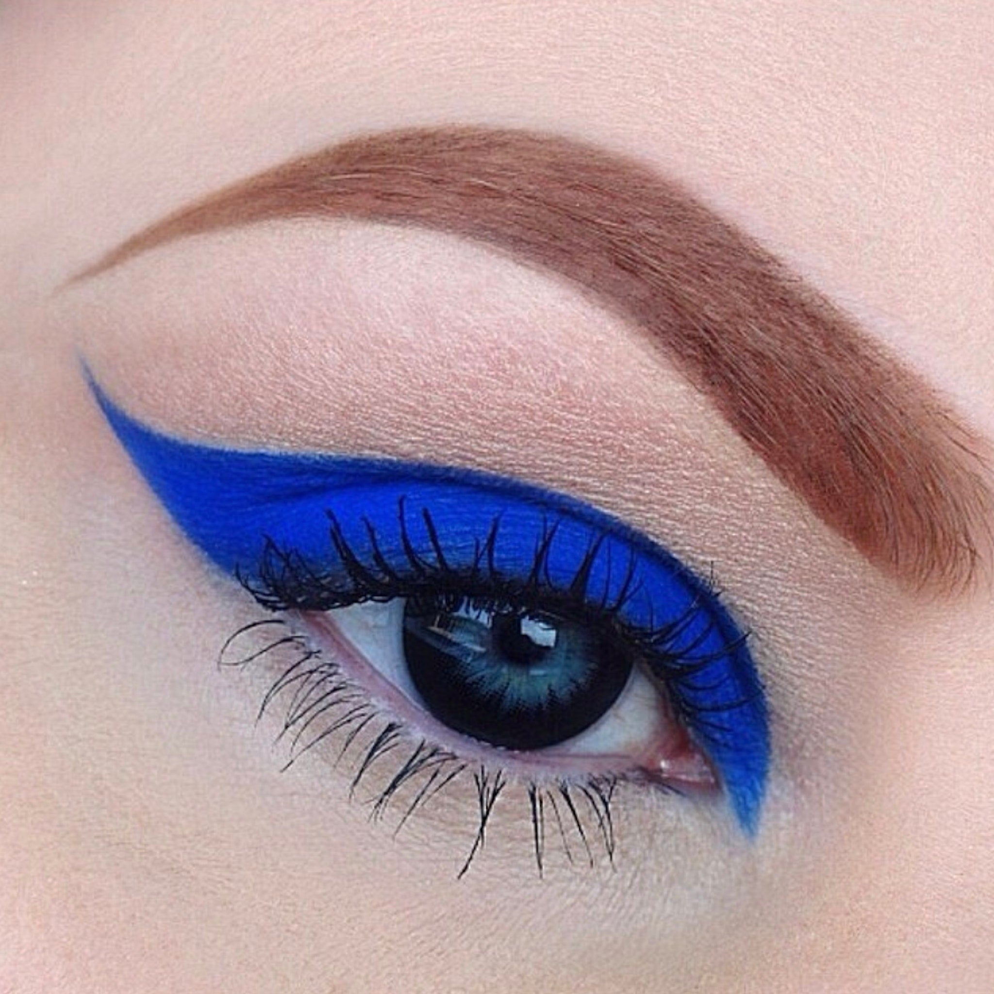 Blue eyeliner makeup with dark lashes and brown eyebrow on an eye