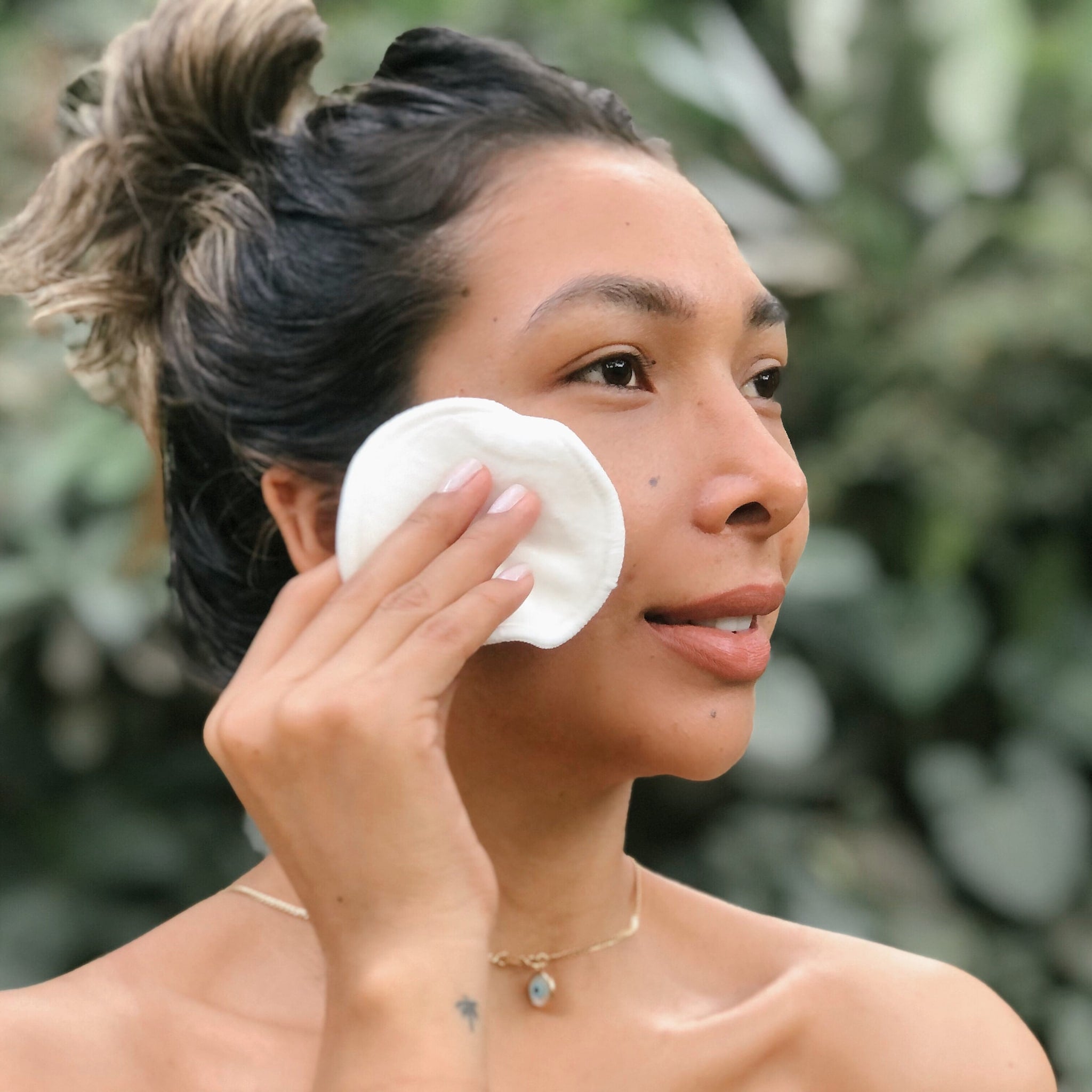 Reusable cotton pad held by a woman, white round pad, used on face
