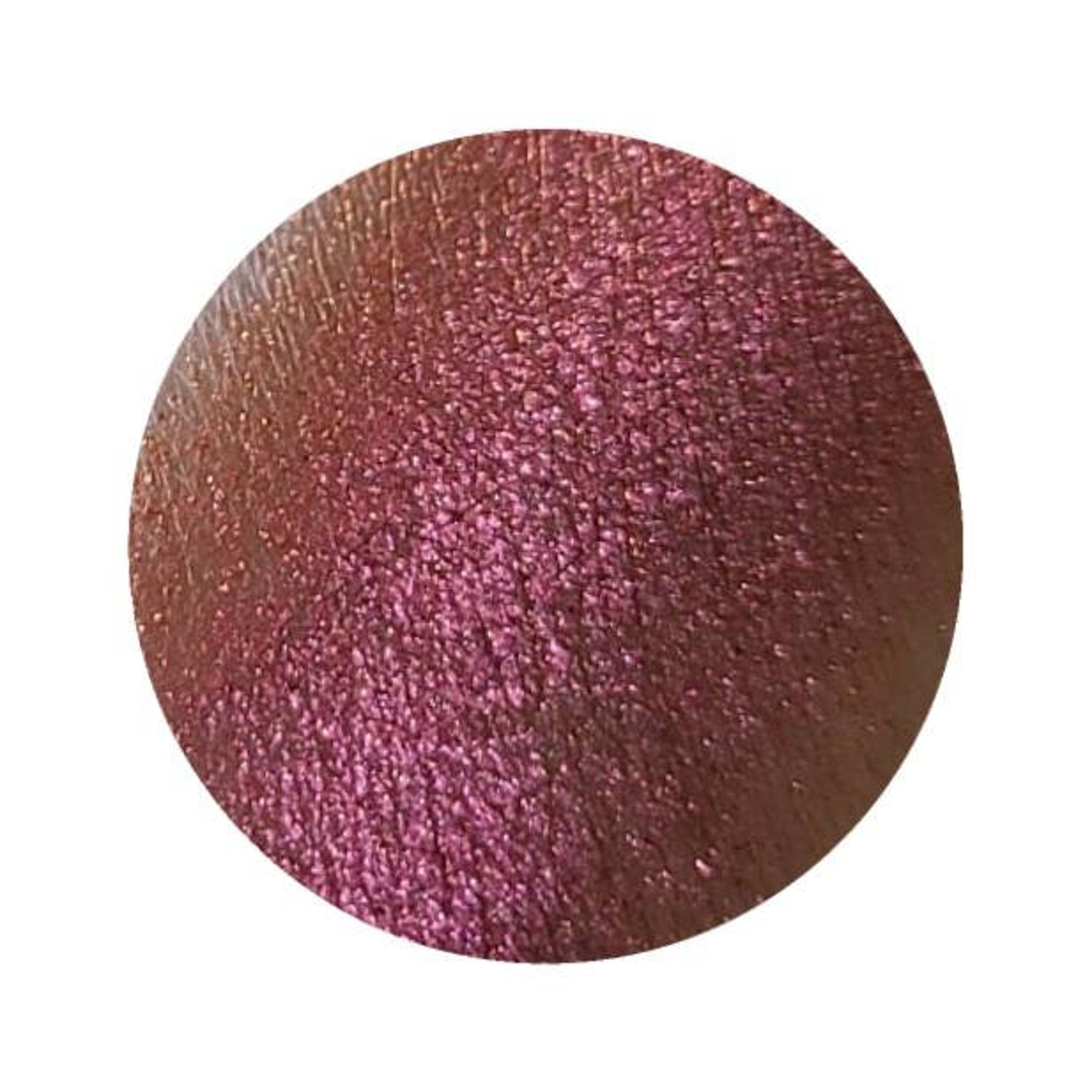 Close-up of NEBULA multichrome eyeshadow pot showing vibrant orange-pink-gold-violet shift in sunlight.