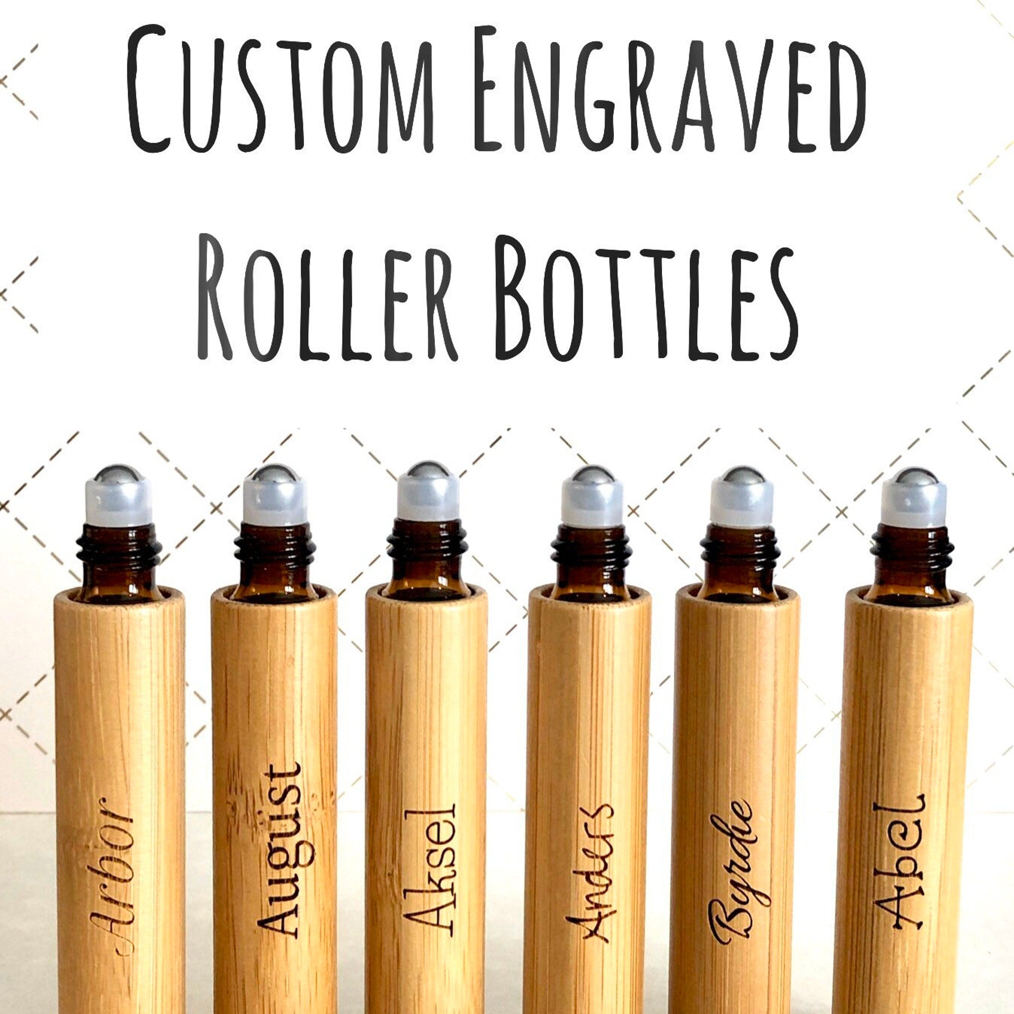 Roller bottles with engraved names, brown glass, bamboo sleeves, and silver rollerball tops