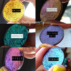 Close-up of multichrome eyeshadow pan with shimmery sparkle applied on eyelid, showing color shift effect