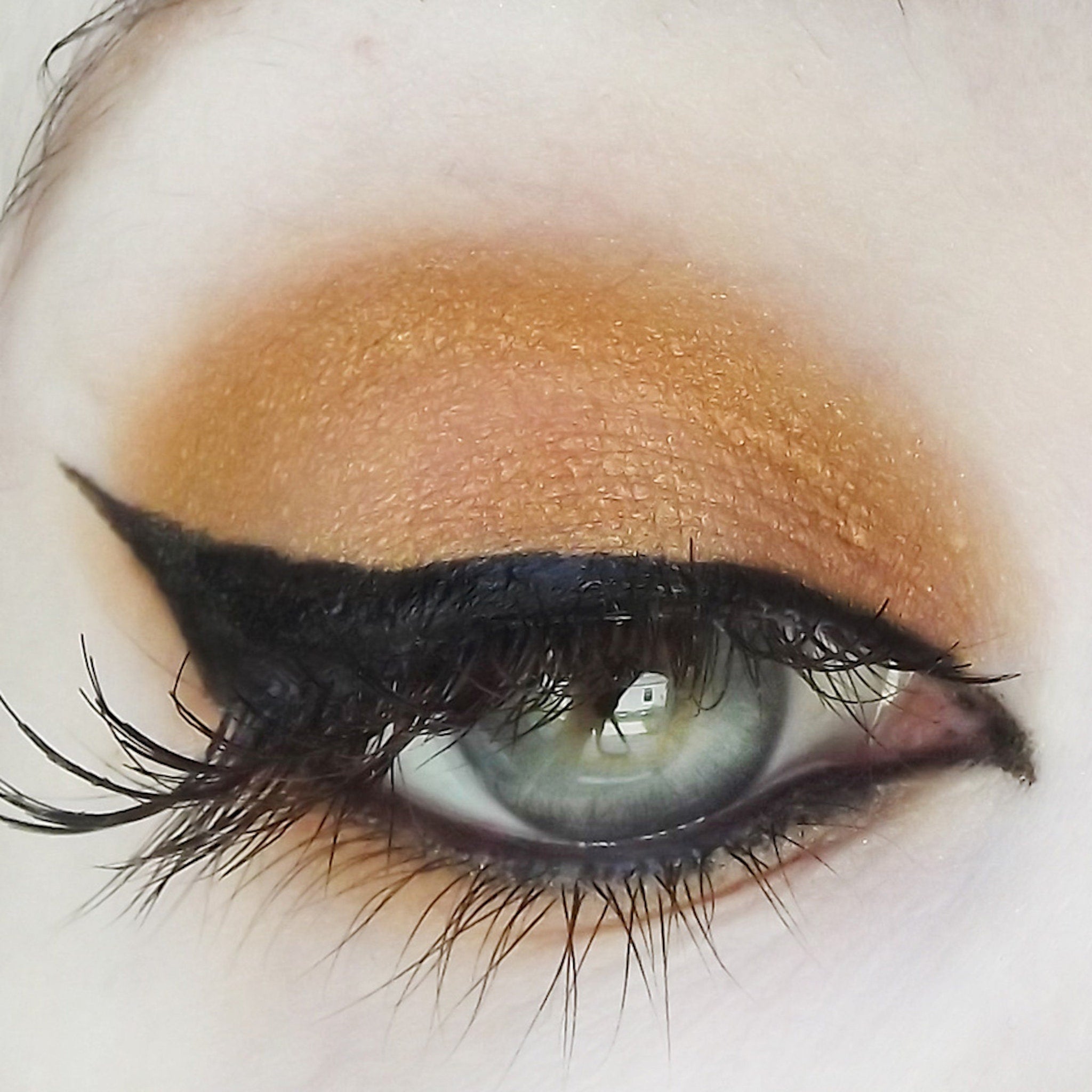 Eyeliner and eyeshadow: black winged eyeliner, gold eyeshadow, green eye with long lashes