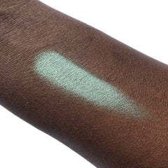 Eyeshadow swatch in mint green color on dark skin, showing texture and application