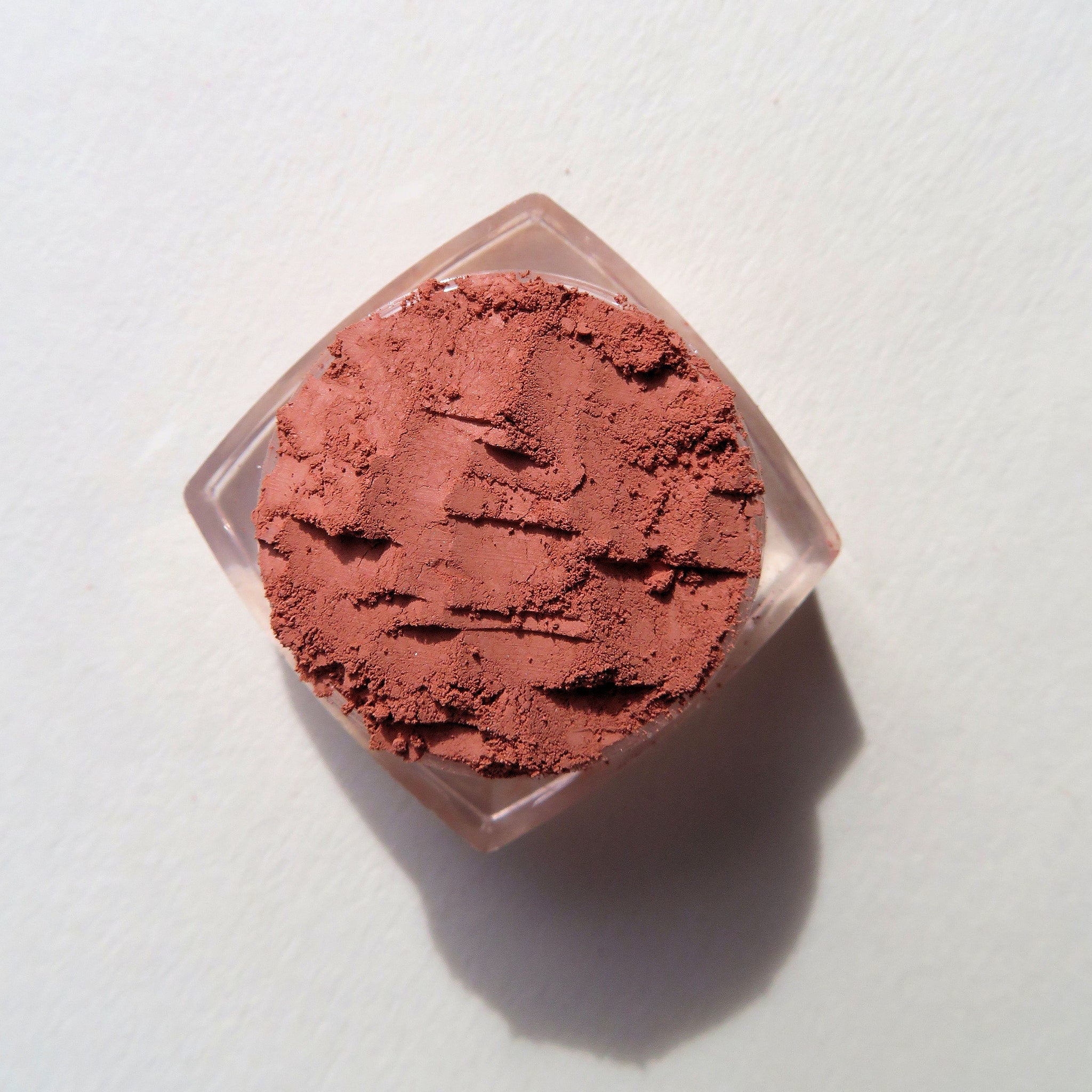 Close-up of vibrant burnt orange loose mineral eyeshadow with matte finish in eco-friendly packaging