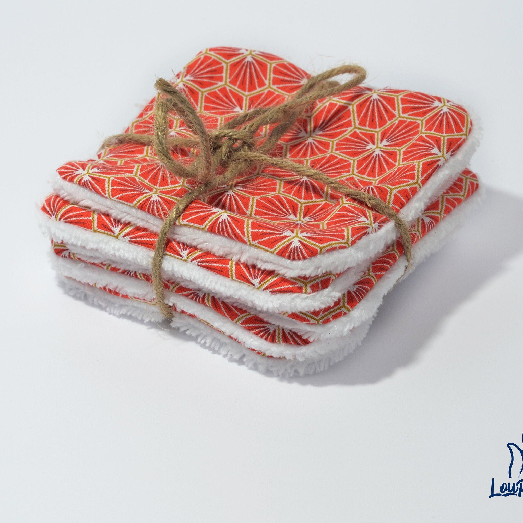 Reusable face pads with red geometric pattern, white trim, and tied with twine