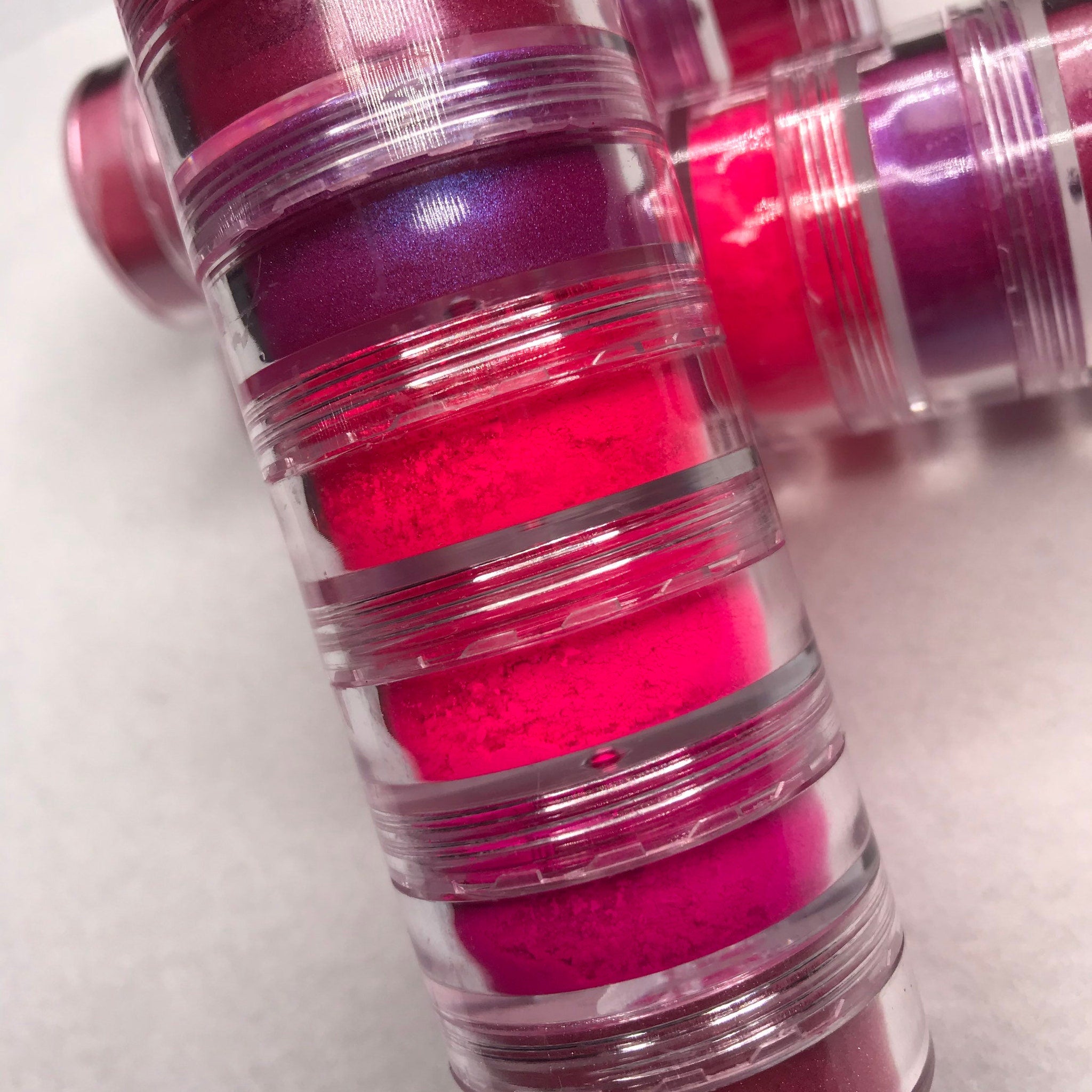 Swatch of six neon pink eyeshadows showing matte and shimmer textures on fingertips