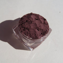 Eyeshadow powder in dark purple with glitter, in clear plastic jar, close-up shot