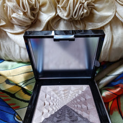 Highlighter compact with black frame, silver shimmer, and geometric pattern design