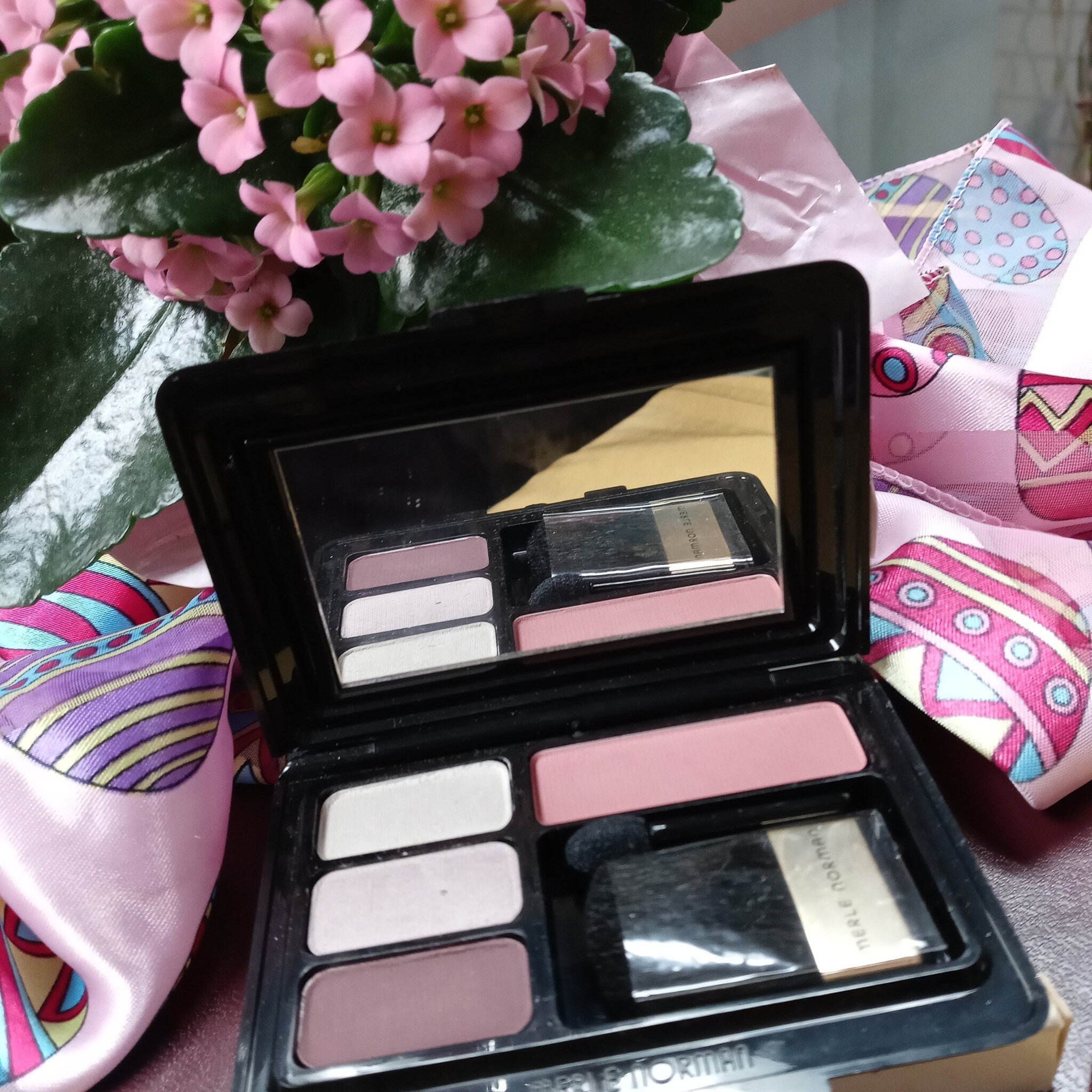 Eye shadow palette with black compact, pink and neutral shades, and Merle Norman text visible
