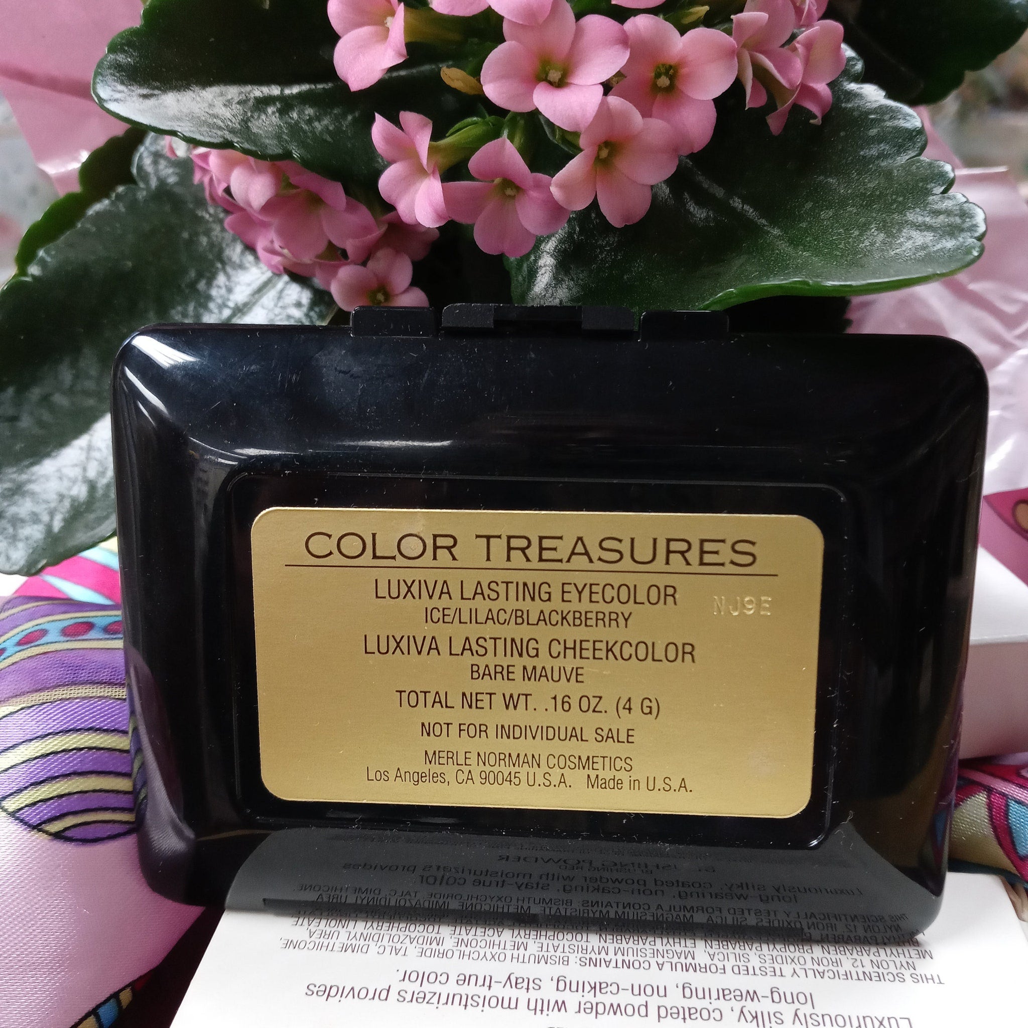 Black compact with gold label and pink flowers, Merle Norman Color Treasures visible