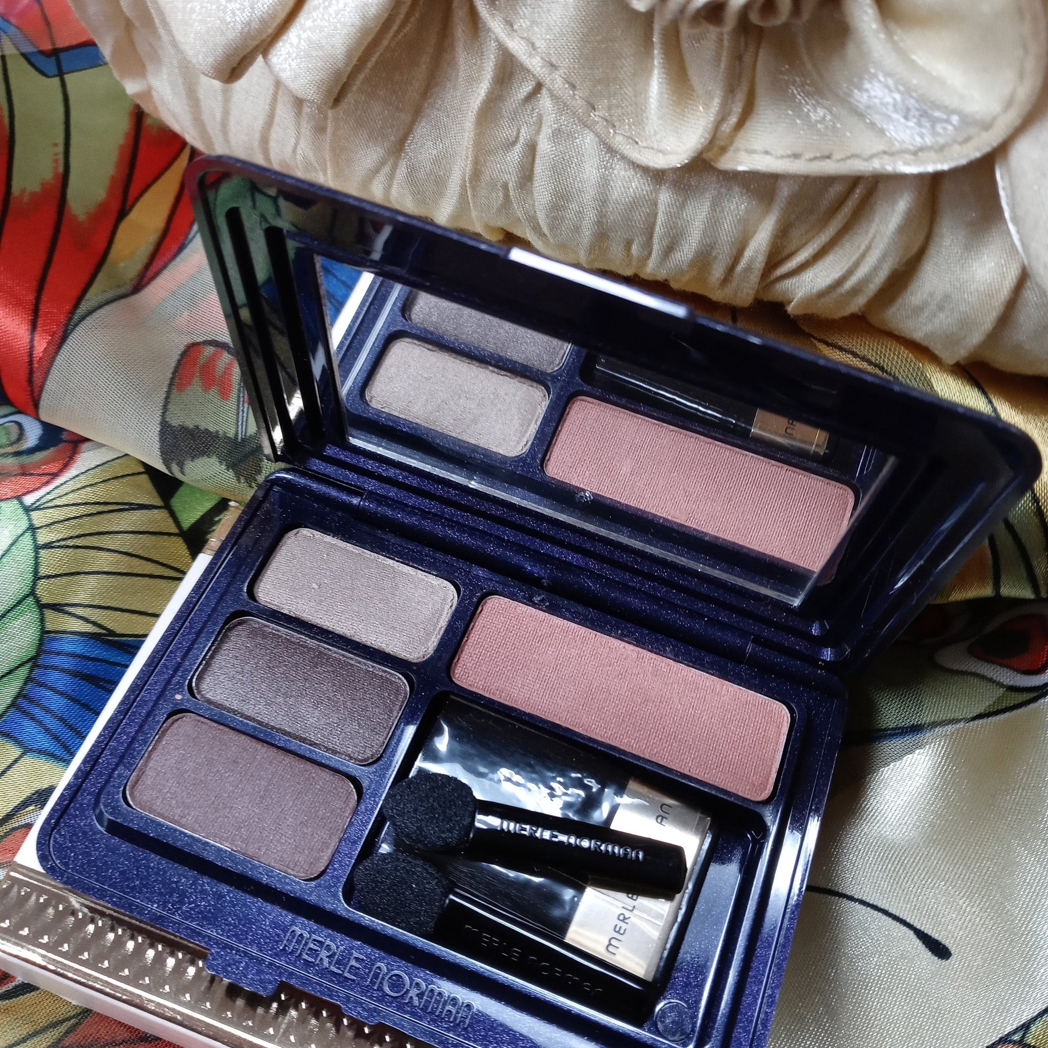 Eyeshadow palette with multiple shades of brown and pink, Merle Norman brand, with applicators