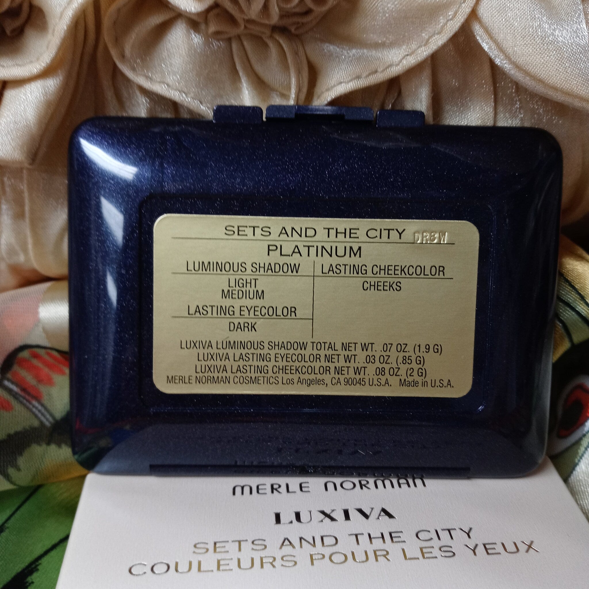 Makeup compact with navy blue case, gold label, and Merle Norman brand text visible