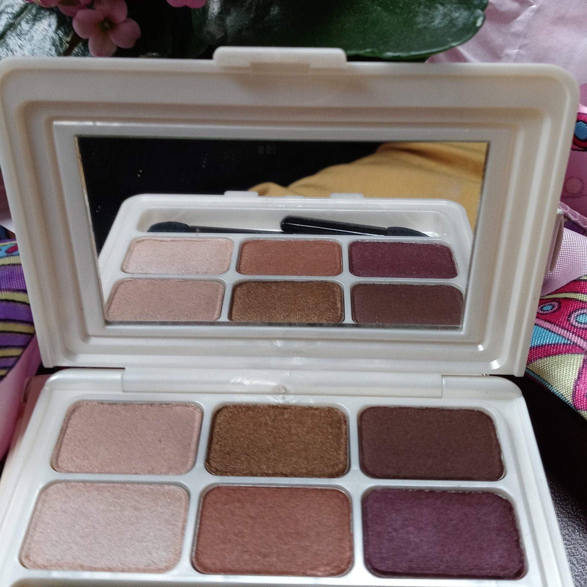 Hand applying shimmery champagne eyeshadow from compact with brush, blending onto eyelid