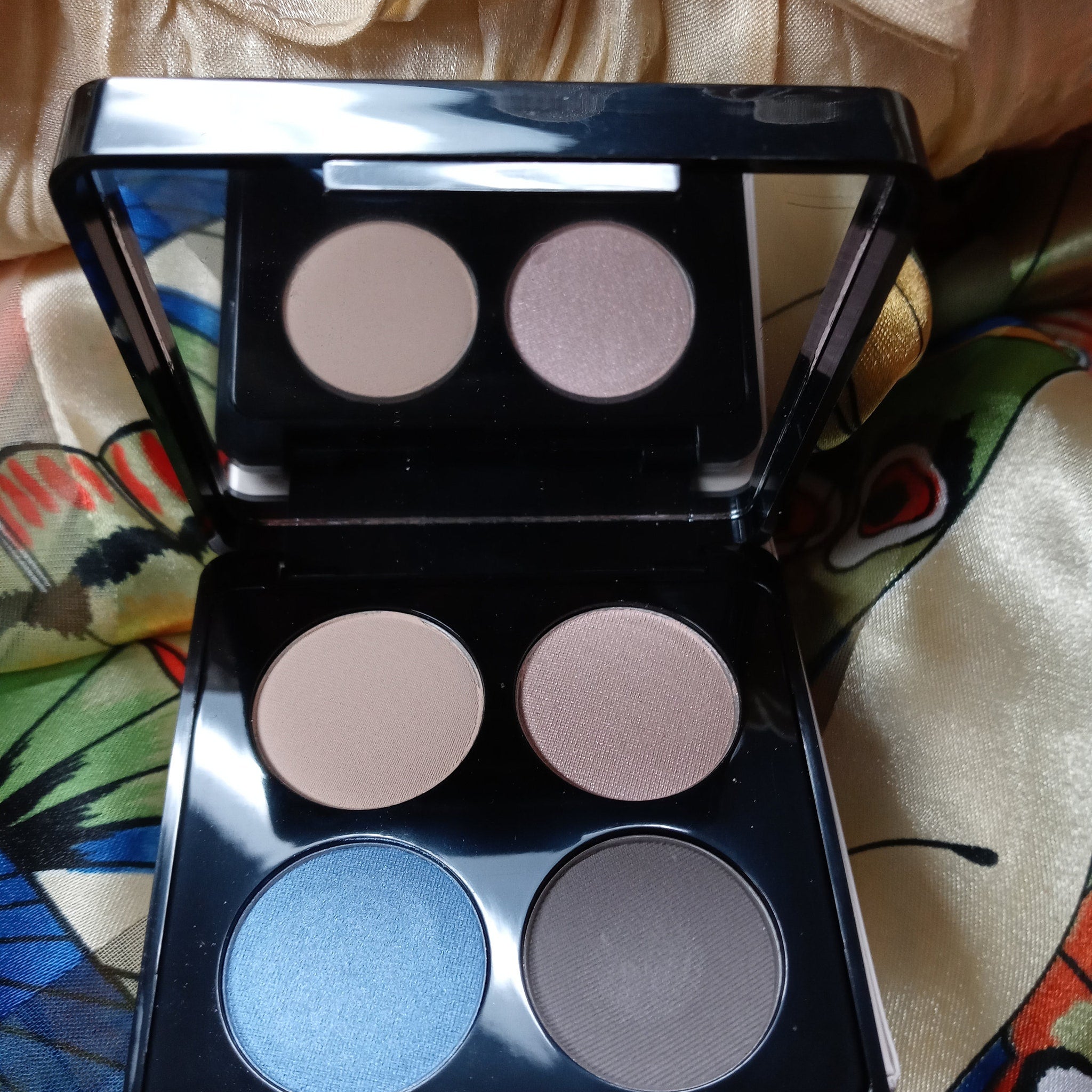 Close-up of a makeup brush applying shimmering taupe eyeshadow from the quad palette