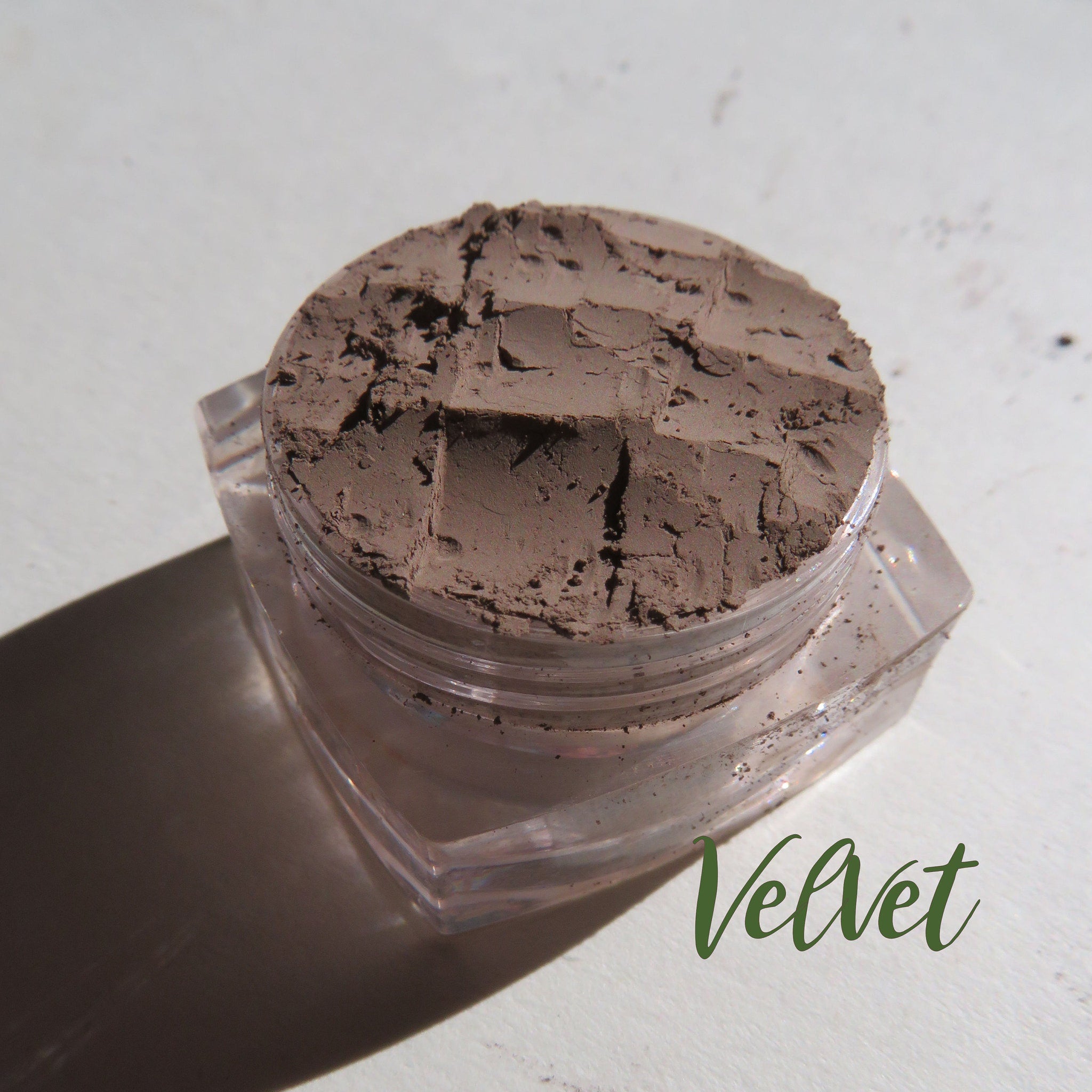 Open compact showing matte brown mineral eye shadow and eyebrow powder with dual compartments and small brush.