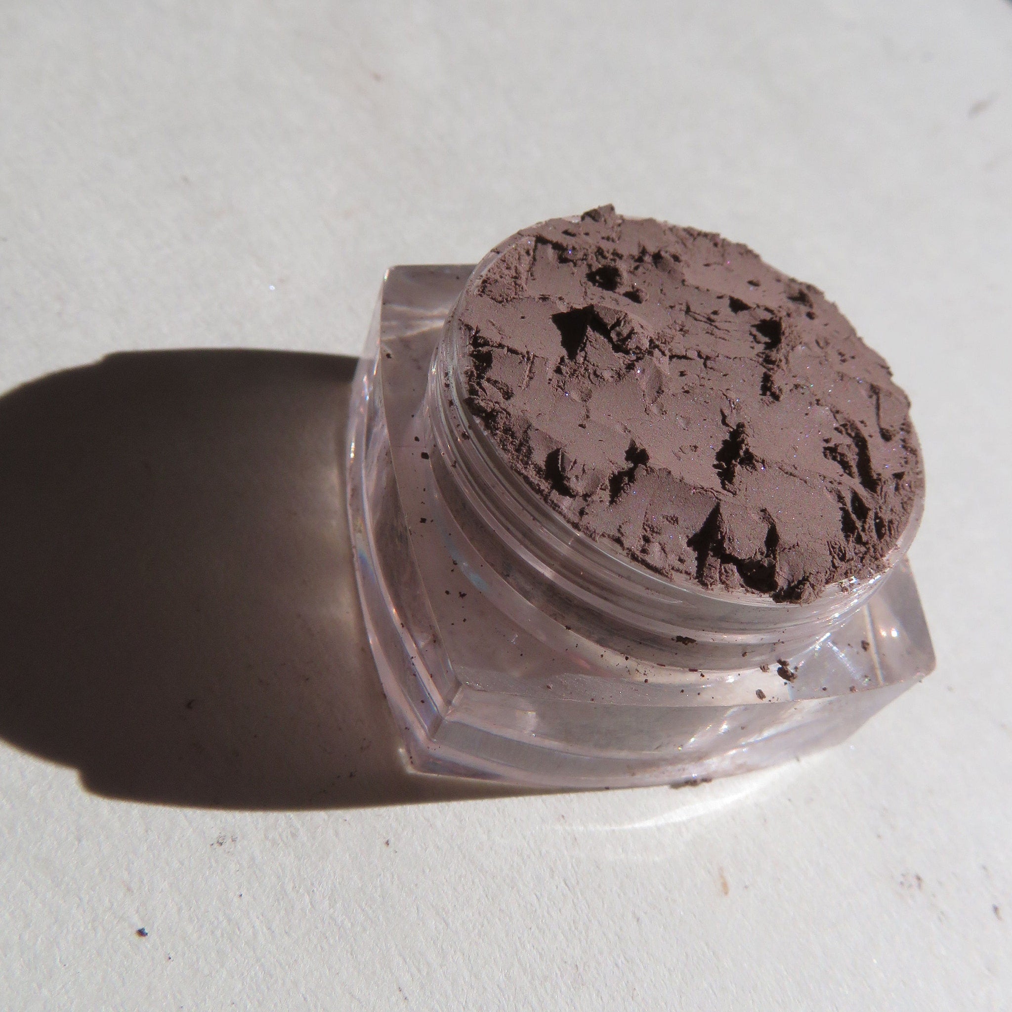 Side view of matte brown mineral eye shadow set showing loose pigment texture in compact jar